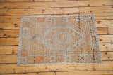 Distressed Oushak rug corner showing its decorative faded platinum and vibrant orange weave.