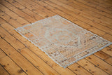 Distressed Oushak rug corner, showing textured pile in platinum, orange, and brown.
