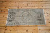 Faded germinating flower motifs in charcoal, pale rose, and slate on a distressed Oushak rug.