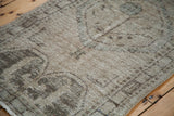 Distressed Oushak rug texture revealing faded curvilinear floral motifs in muted tones.