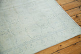 Distressed Oushak rug corner with soft ivory, faded lemon silver and blue-grey border.