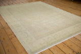 Distressed Oushak rug corner, featuring soft beige gold pile and faded rose patterns.