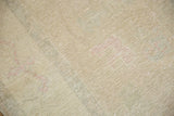 Distressed Oushak carpet showing its soft beige gold and light rose worn pile.