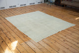 Fringed edge of the distressed Oushak carpet, with pale silver and faded earth tones.