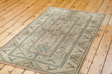 Distressed Oushak rug showing blanched sand and ivory tones with muted blue motifs.