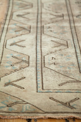 Softened pile of distressed Oushak rug with blanched sand and faded blue geometric designs.