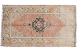 Faded vintage Turkish Oushak rug with orangey rose and charcoal medallion on ivory.