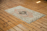 Faded orangey rose, ivory, and charcoal patterns on a vintage Oushak rug corner.