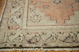 Vintage Oushak rug's faded orangey rose, ivory geometric border with softened pile and fringe.