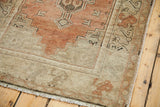 Faded orangey rose field, geometric pale ivory border, and white fringe on a vintage Oushak rug.