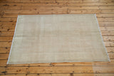 Worn rose ivory white texture on the distressed Oushak rug's lower right corner.