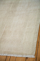 Worn texture of distressed Oushak rug in rose ivory with white fringe.