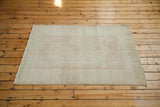 Distressed Oushak rug with a soft, worn texture in muted ivory and golden tones.