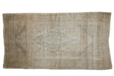 Distressed Oushak rug featuring a subtle medallion pattern in pale earth tones.