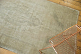 Distressed vintage Oushak rug texture featuring faded medallion in pale beige and silver ivory.