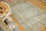 Distressed texture and subtle faded pattern of a vintage Oushak rug in pale beige and grey.