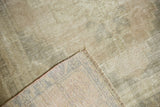 Distressed Oushak rug pile texture with pale earth tones and woven foundation detail.