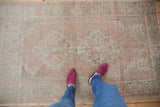 Distressed vintage Oushak rug texture with faded brick rose and geometric tribal patterns.