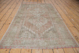 Distressed Oushak rug corner, faded brick rose and green tribal geometric pattern, with fringe.
