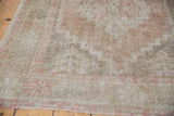 Distressed Oushak rug with faded brick rose and muted beige tribal geometric texture.