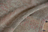 Close-up of distressed Oushak rug pile, showing faded brick rose color and soft texture.