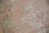 Detailed view of distressed Oushak pile with faded brick rose and zigzag motif.