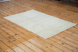 Airy blanched ivory, grey, and platinum tones on a distressed Oushak rug corner.