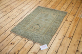 Distressed Oushak rug showing faded silver field and strong geometric border motifs.