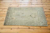 Distressed Oushak rug corner showing geometric border and soft silver pile.