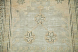 Textured pile of a distressed Oushak rug showing geometric motifs in softened silver and beige.