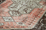 Decorative detail of distressed Oushak rug, pale rose and chocolate geometric patterns.