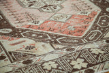 Distressed Oushak rug pile showing pale rose, brick, and brown motifs.
