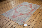 Softened brick red, creamy ivory, and silver grey floral motifs on a distressed Oushak corner.