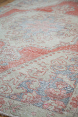 Distressed Oushak rug detail with bright brick red field and creamy ivory curvilinear motifs.