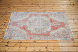 Distressed Oushak rug corner detail with brilliant brick red, creamy ivory, faded blue motifs.