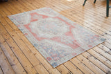 Distressed Oushak rug corner, revealing worn pile, short fringe, creamy ivory, brick red.