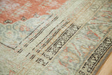 Vintage Oushak rug's intricate muted green border with dark patterns against a brick orange field.