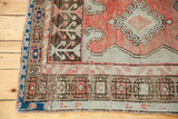 Vintage Oushak rug corner detail, highlighting tribal geometric borders in coral, brown, and blue.