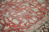Vintage Oushak rug with distressed red field, flowing ivory vines, and charcoal border.