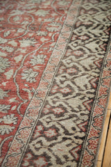 Distressed red field with scrolling vines transitioning to grey and ivory patterned border.