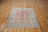 Distressed vintage Oushak rug corner, faded red field, scrolling vines, charcoal and ivory border.