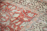 Evenly worn glowing red field with ivory scrolling vines and charcoal border motif.