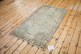 Vintage Oushak rug corner showing bronze, beige, and silver border design.