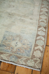 Corner of a vintage Oushak rug, showing bronze border motifs and muted beige field.