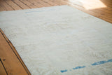 Distressed Oushak rug's blanched texture revealing sandy beige patterns and aqua blue abrash.