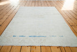 Faded snow white Oushak rug end, with distinct aqua blue abrash and soft fringe.