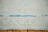Distressed Oushak rug pile with blanched sandy beige tones, aqua blue abrash, and fringe.