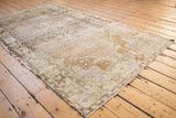 Distressed Oushak rug texture and muted curvilinear pattern in pale beige and ivory.