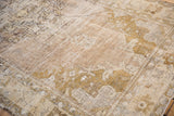 Distressed Oushak rug close-up, showcasing textural pile with muted ivory, grey, bronze patterns.