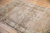 Textural side view of the distressed Oushak rug with faded curvilinear motifs in beige.